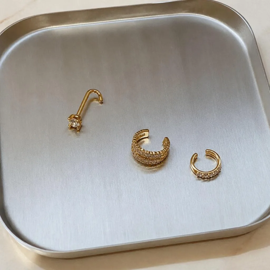 Diamond nose pin and ear cuffs on a steel tray